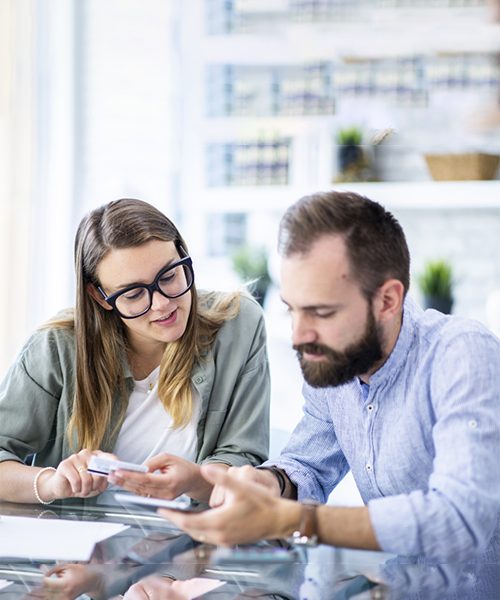 Two people discussing with smartphones at table.