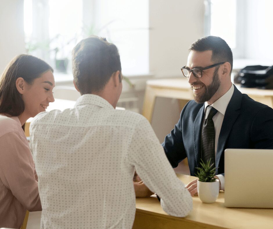 A business meeting with three professionals discussing work in a bright office.