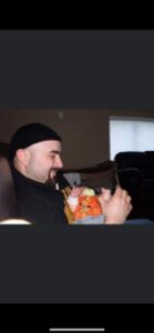 Man holding a small child dressed in colorful clothes indoors.