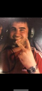 Young man smiling and making a peace sign gesture.