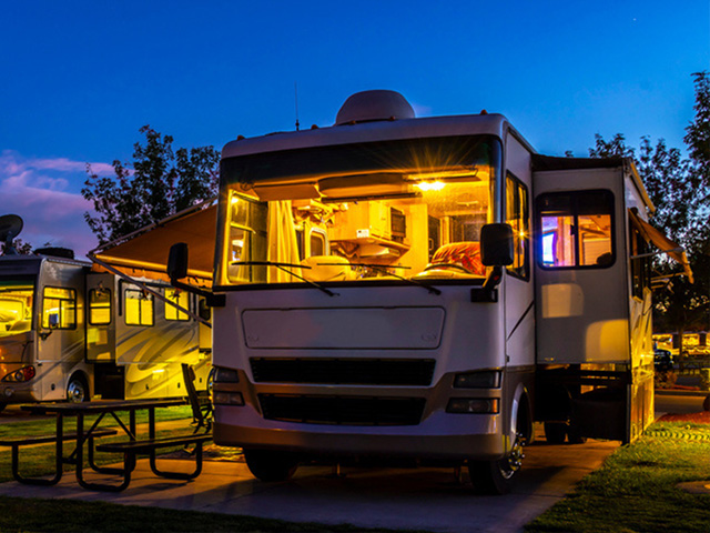 Illuminated RV at a campsite during twilight - https://brancoinsurancegroup.com/