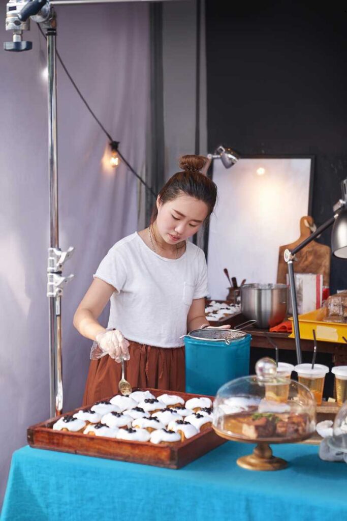 Young woman in a white shirt decorates pastries on a blue table in a cozy kitchen