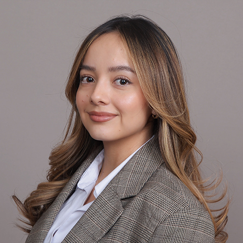 Young woman in a blazer smiling softly.