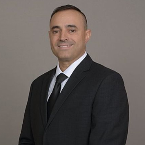 Smiling man in a black suit and tie.