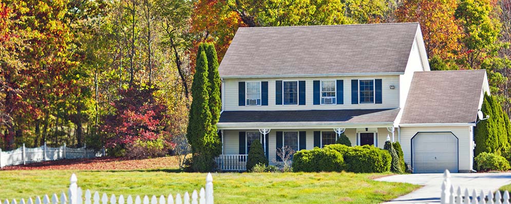 A charming house with a white picket fence surrounded by a well-maintained green lawn