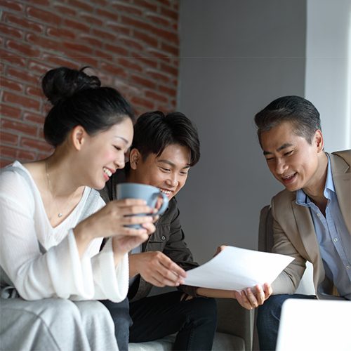 Three colleagues reviewing documents together with smiles.