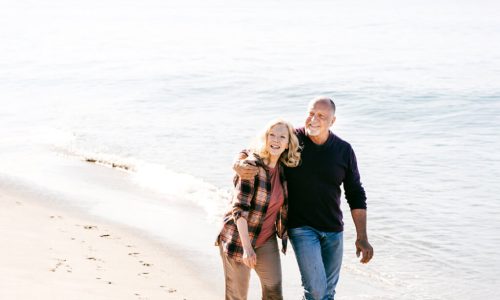 Couple walking hand-in-hand on a sunny beach.