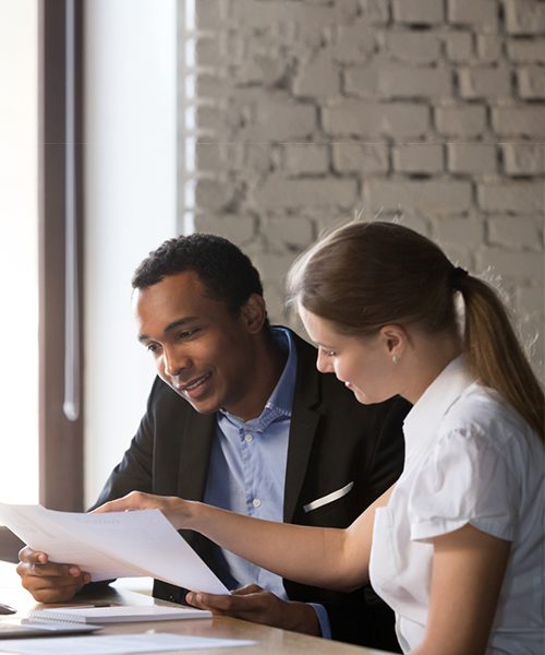 Two colleagues reviewing documents together in an office.