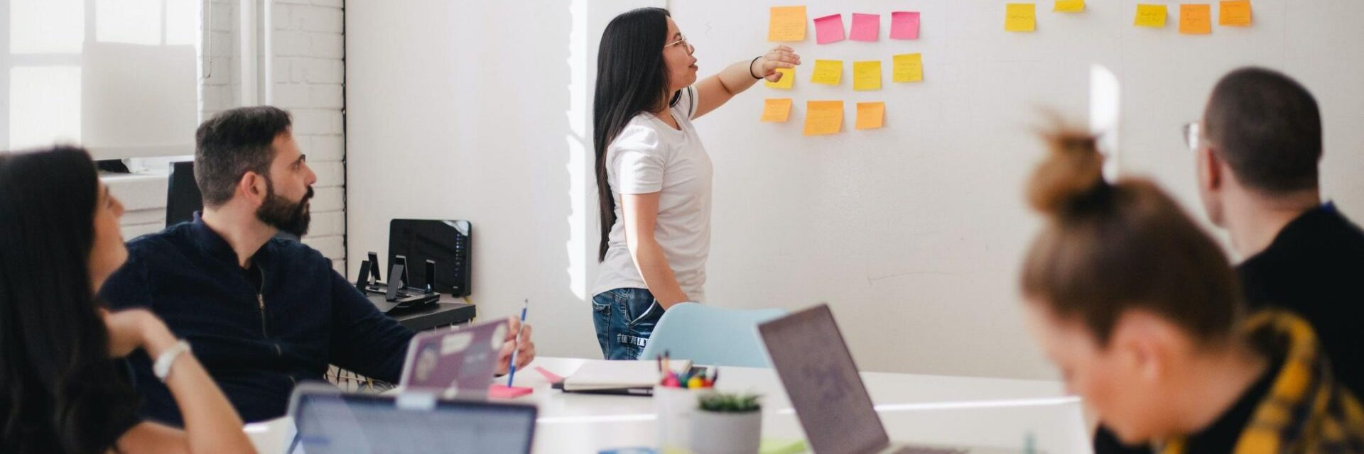 Woman placing sticky notes on a wall during a brainstorming session.